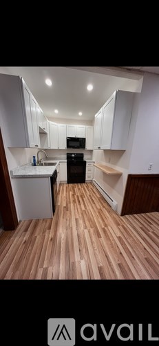 A kitchen with white cabinets and wooden flooring.
