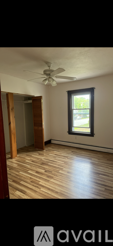 A room with a ceiling fan and wooden flooring.