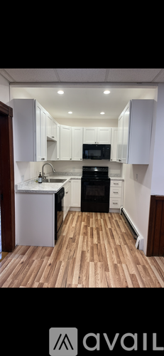 A kitchen with white cabinets and a wooden floor.