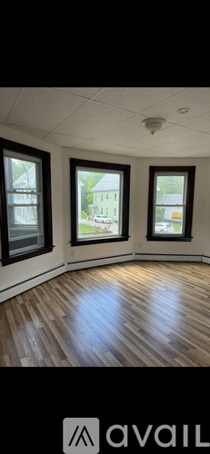 A room with wooden floors and three windows.