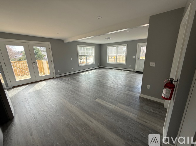 A spacious room with grey flooring and a large window.