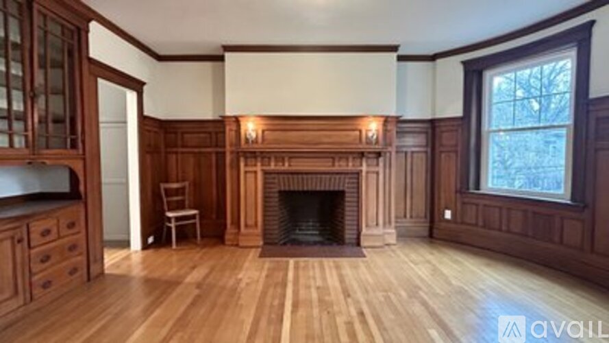A large, empty room with wood floors and a fireplace.