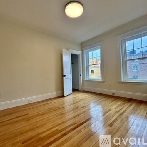 A room with wooden flooring and a window showing a building outside.
