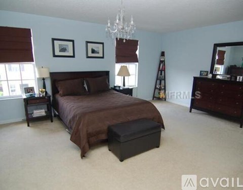 A bedroom with a large bed and a chandelier.