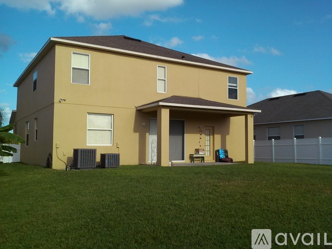 A beige house with a brown roof and a green lawn in front.