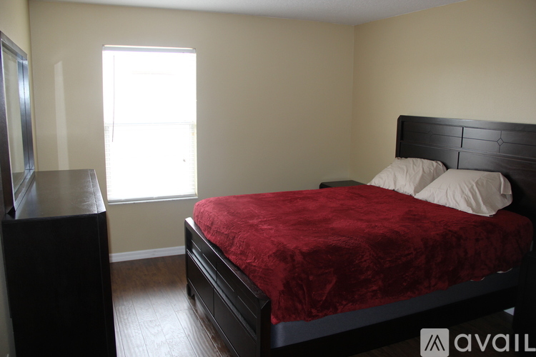 A bedroom with a red bedspread and a black headboard.