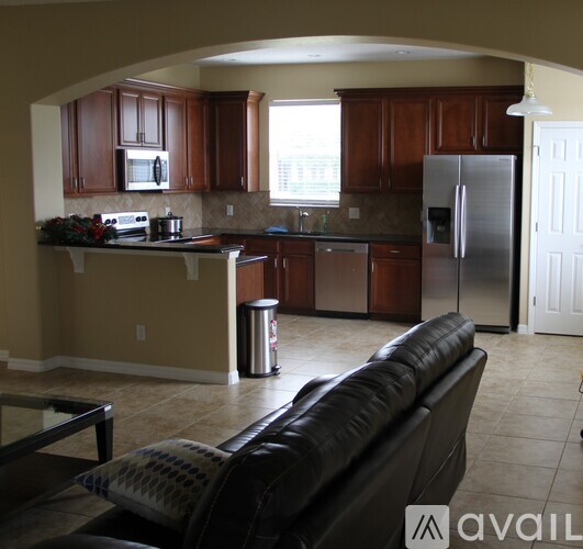 A kitchen with brown cabinets and a black couch.