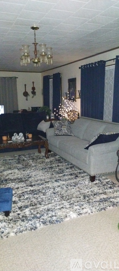 A living room with a grey couch and a chandelier.
