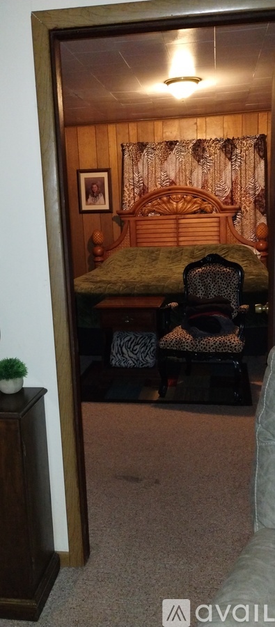 A bedroom with a bed, chair, and picture on the wall.
