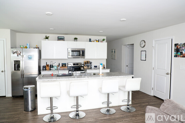 A kitchen with white appliances and white bar stools.