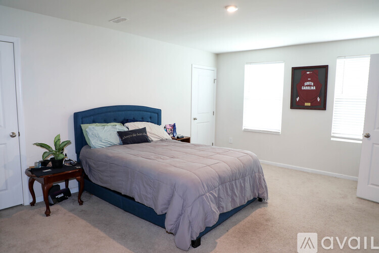 A bedroom with a bed, nightstand, and a plant.