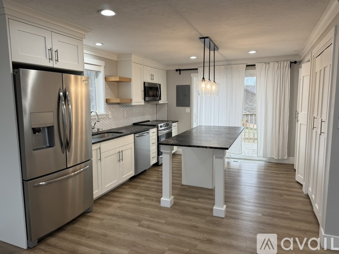 A modern kitchen with a stainless steel refrigerator and wooden flooring.
