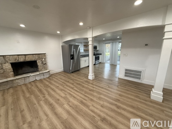 A spacious living room with a stone fireplace and hardwood flooring.