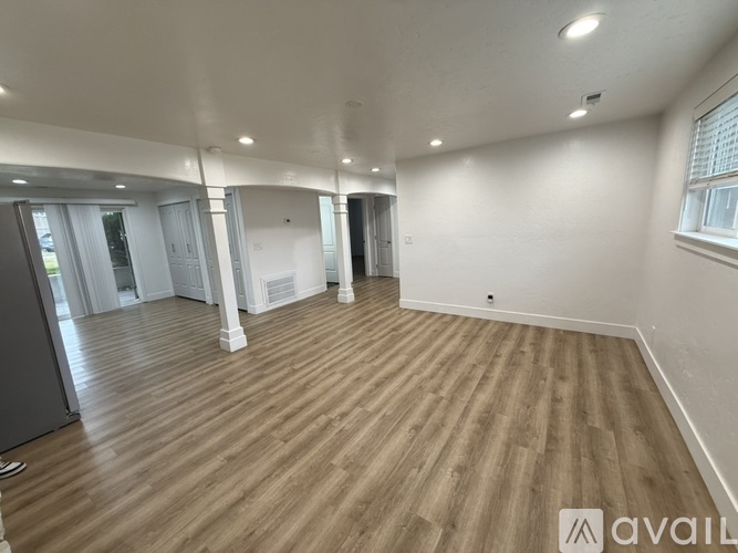 A spacious room with wooden flooring and white walls.