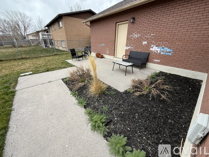 A brick building with a brown door and a small garden in front.