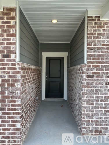A black door is at the end of a hallway with brick walls on either side.