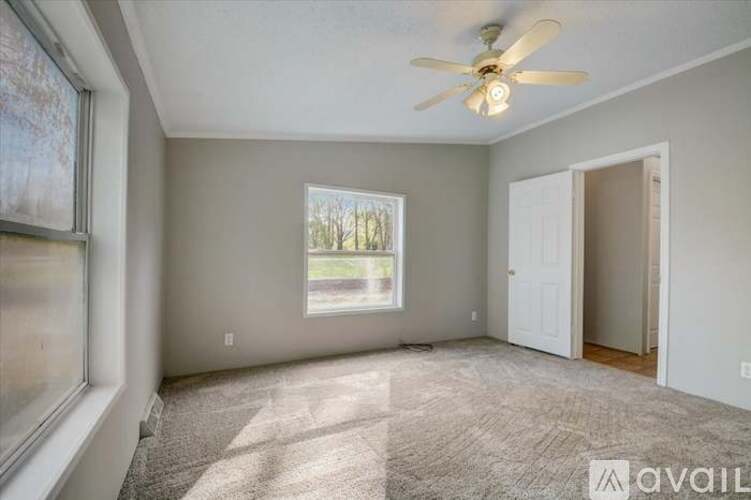 A room with a ceiling fan and a window with a view of trees.