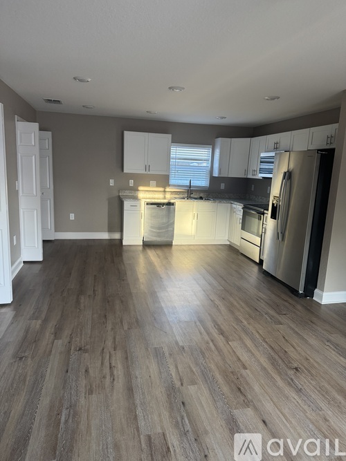 A kitchen with wooden flooring and white appliances.
