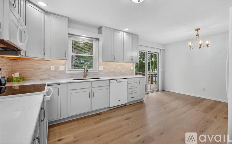 A kitchen with white appliances and wooden floors.