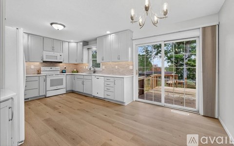 A kitchen with white cabinets and a wooden floor.