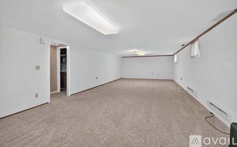 A spacious room with carpeted floor and white walls.