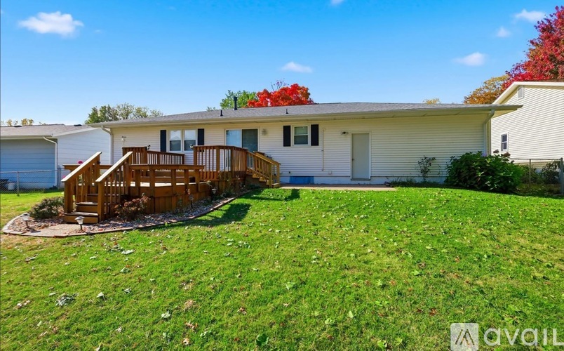 A house with a white exterior and a deck in the front yard.