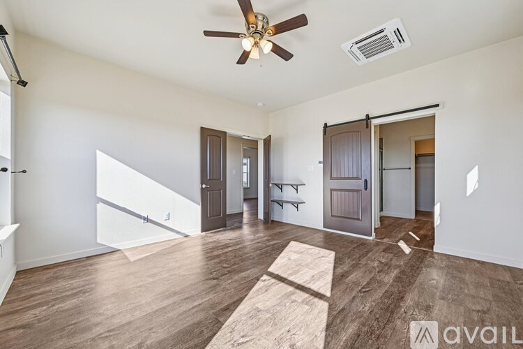 A spacious room with a ceiling fan and wooden flooring.