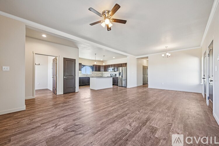 A spacious living room with a ceiling fan and hardwood flooring.