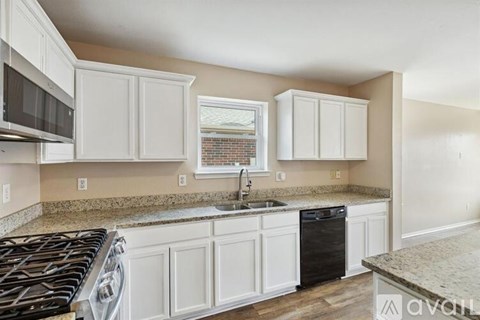 A kitchen with white cabinets and a black stove top.