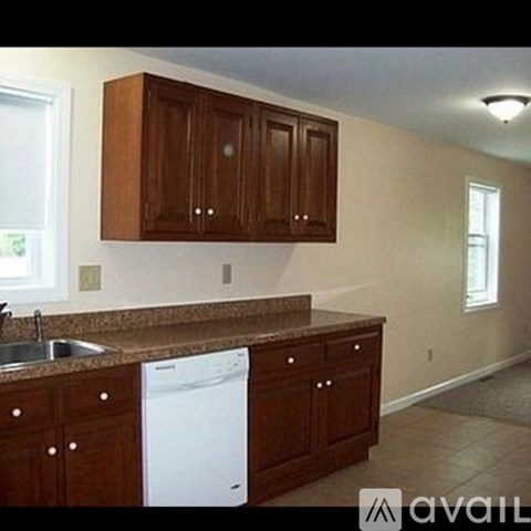 A kitchen with brown cabinets and a white dishwasher.