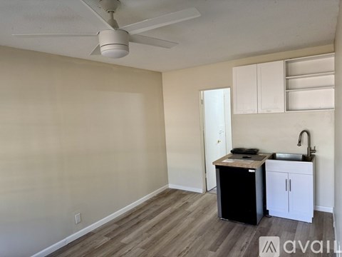 A kitchen area with a black refrigerator, a sink, and a ceiling fan.