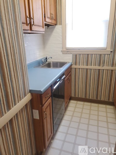 A kitchen with wooden cabinets and a striped wallpaper.
