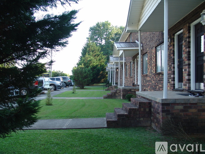 A house with a porch and a tree in front.