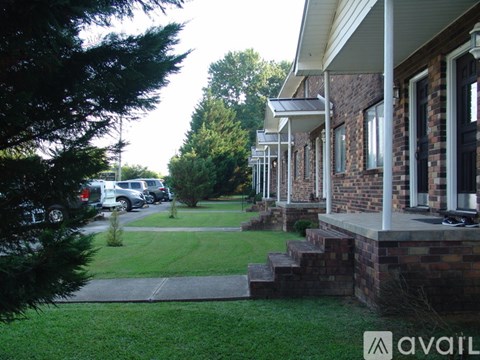 A house with a porch and a tree in front.