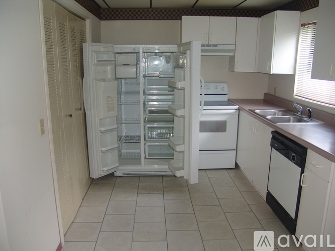 A kitchen with a white fridge and white cabinets.