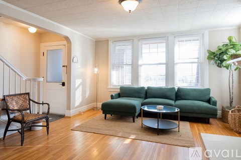 A living room with a green couch and a wooden floor.