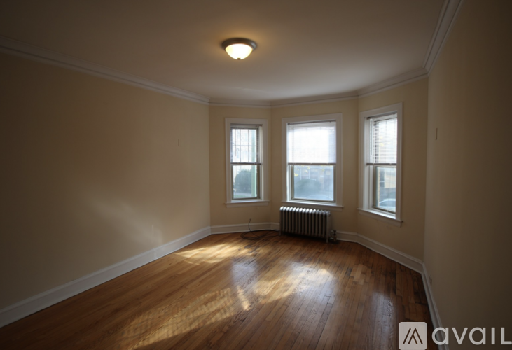 A room with wooden floors and three windows.