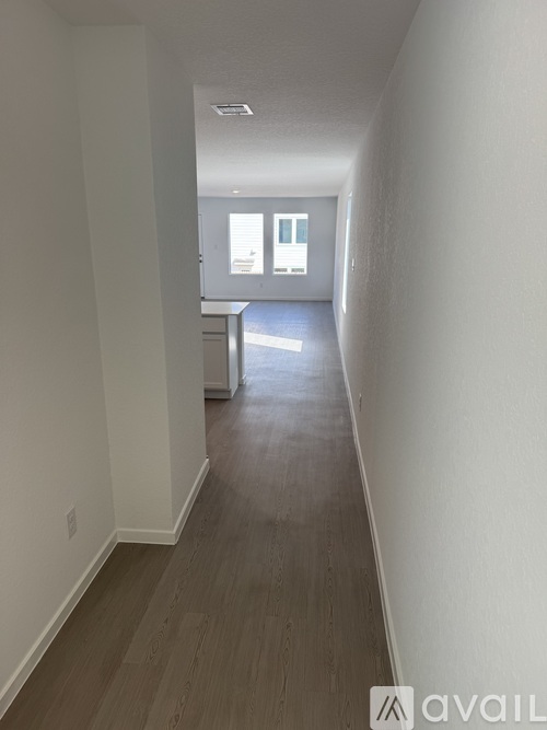 A long hallway with wood floors and white walls.