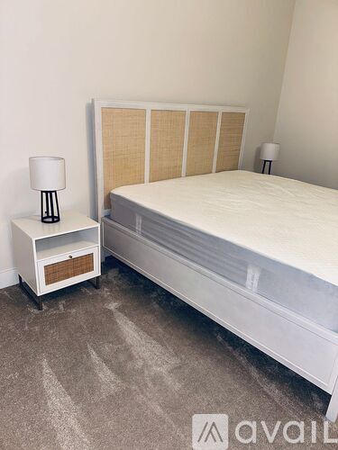 A bedroom with a bed, nightstand, and lamp.