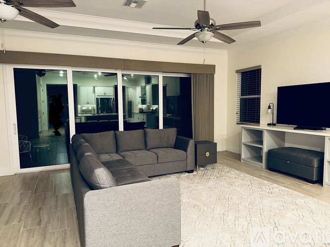 A living room with a grey couch and a ceiling fan.
