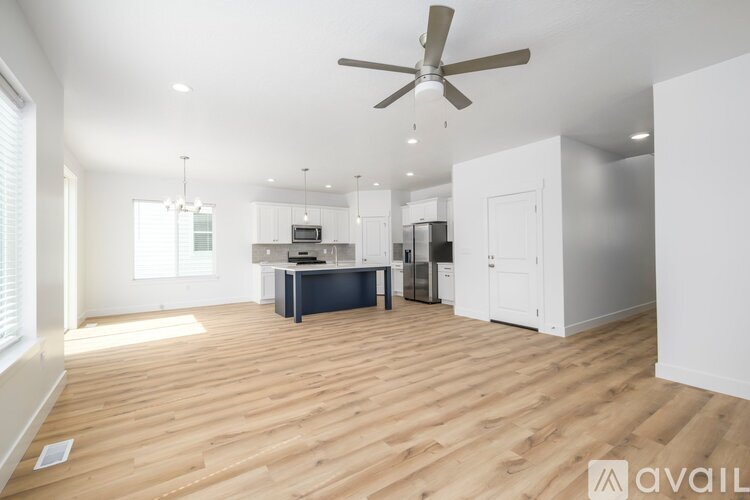 A spacious room with wooden flooring and a ceiling fan.