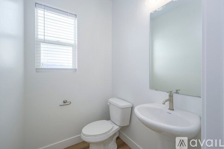 A white toilet sits next to a white sink in a small bathroom.