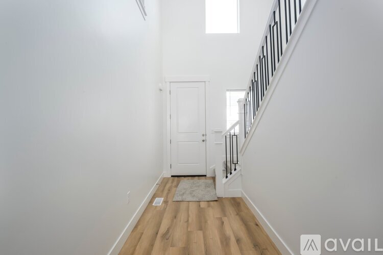 A hallway with a wooden floor and a white door.
