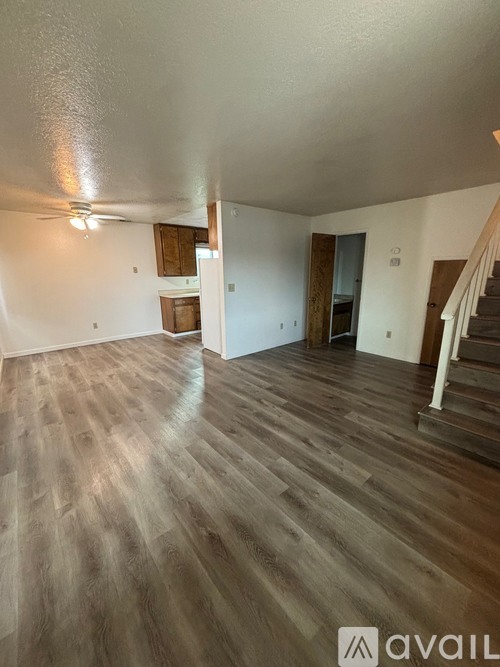 A room with wooden flooring and a staircase on the right side.