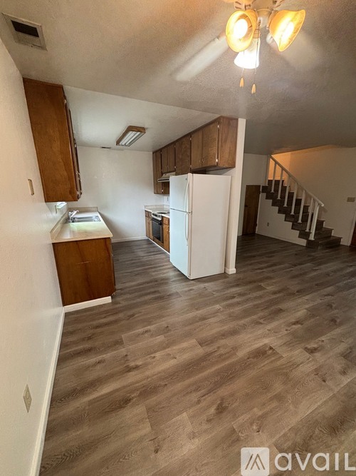 A kitchen area with wooden floors and white appliances.