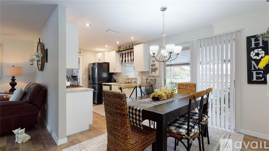 A dining room with a table set for two and a kitchen area in the background.