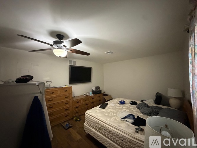 A bedroom with a bed, dresser, and ceiling fan.