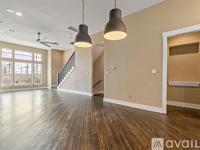 A spacious room with wooden floors and a staircase.