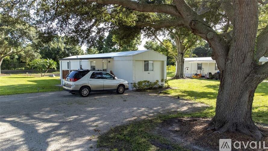 A silver car is parked in front of a white mobile home.