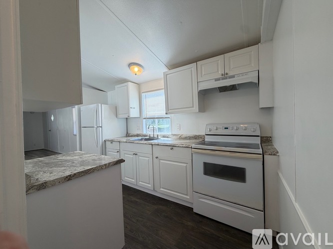 A kitchen with white cabinets and a marble countertop.